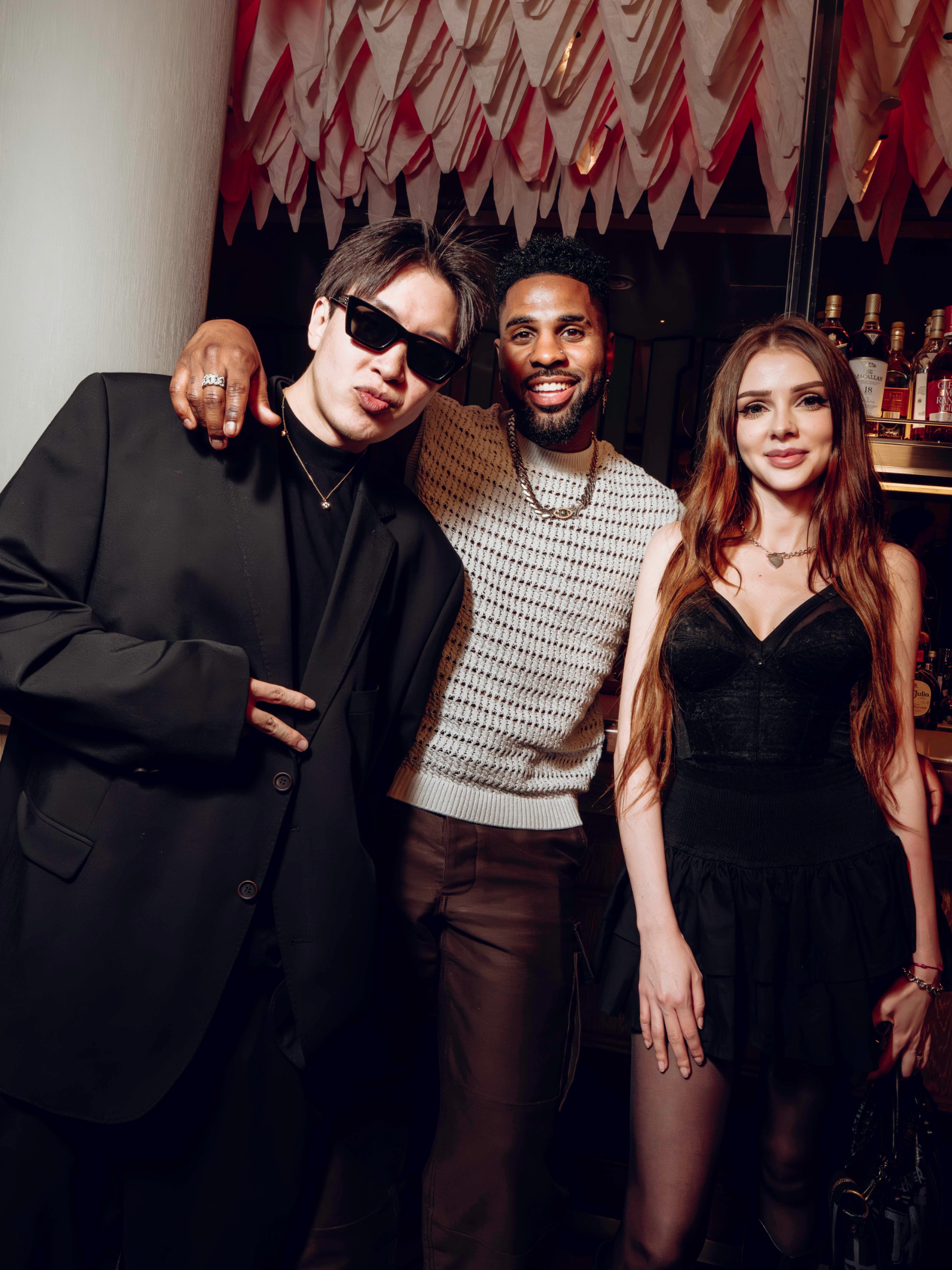 Three guests posing together at an evening gathering.