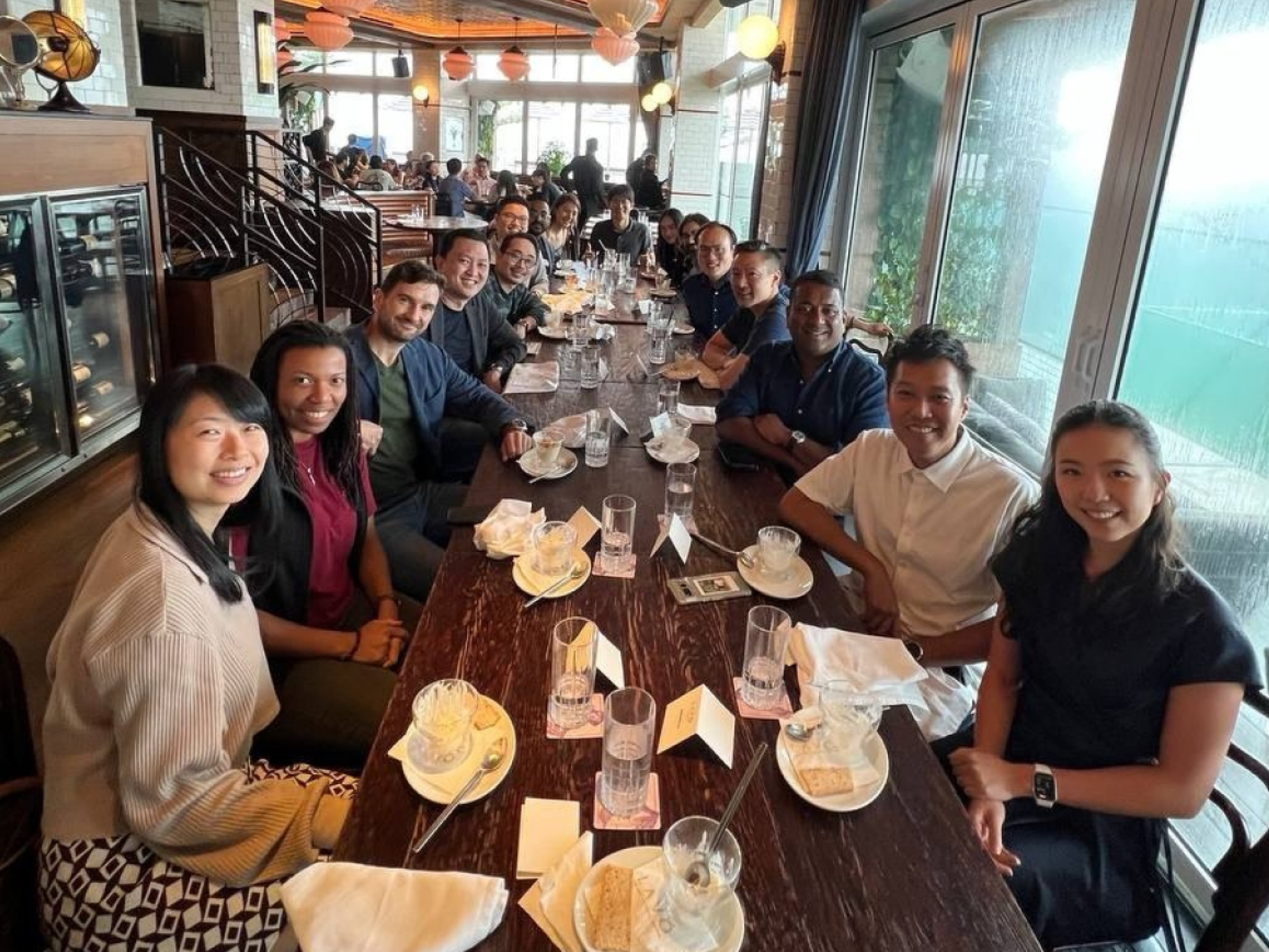 A group seated together around a long table during a daytime gathering.