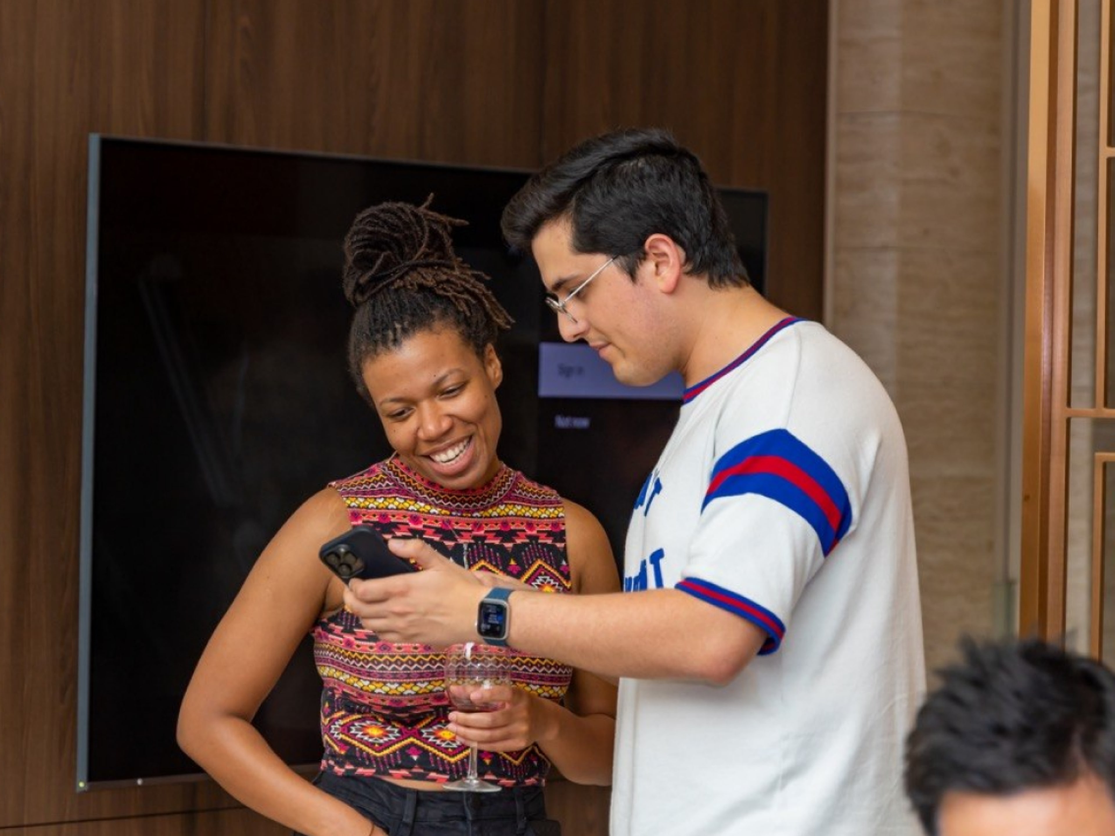 Two guests looking at a phone together during a gathering.